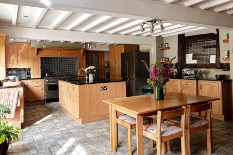 Table in foreground showing farmhouse kitchen