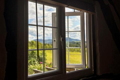Open bedroom window with view over fields and hills in the distance