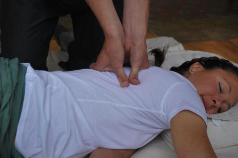Lady lying on front with thumb-pressing her back
