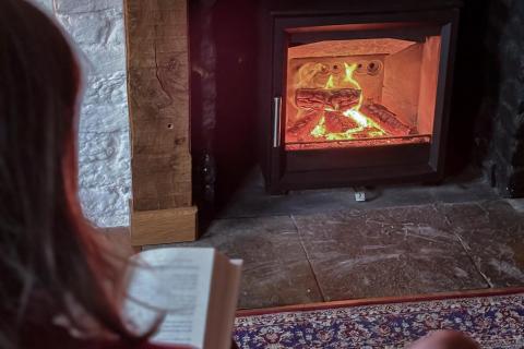 Lady reading by log fire