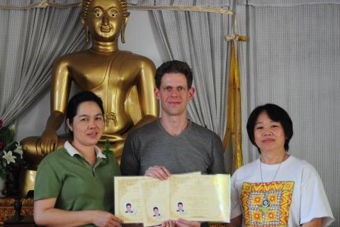 Certificate presentation in front of Thai Buddha